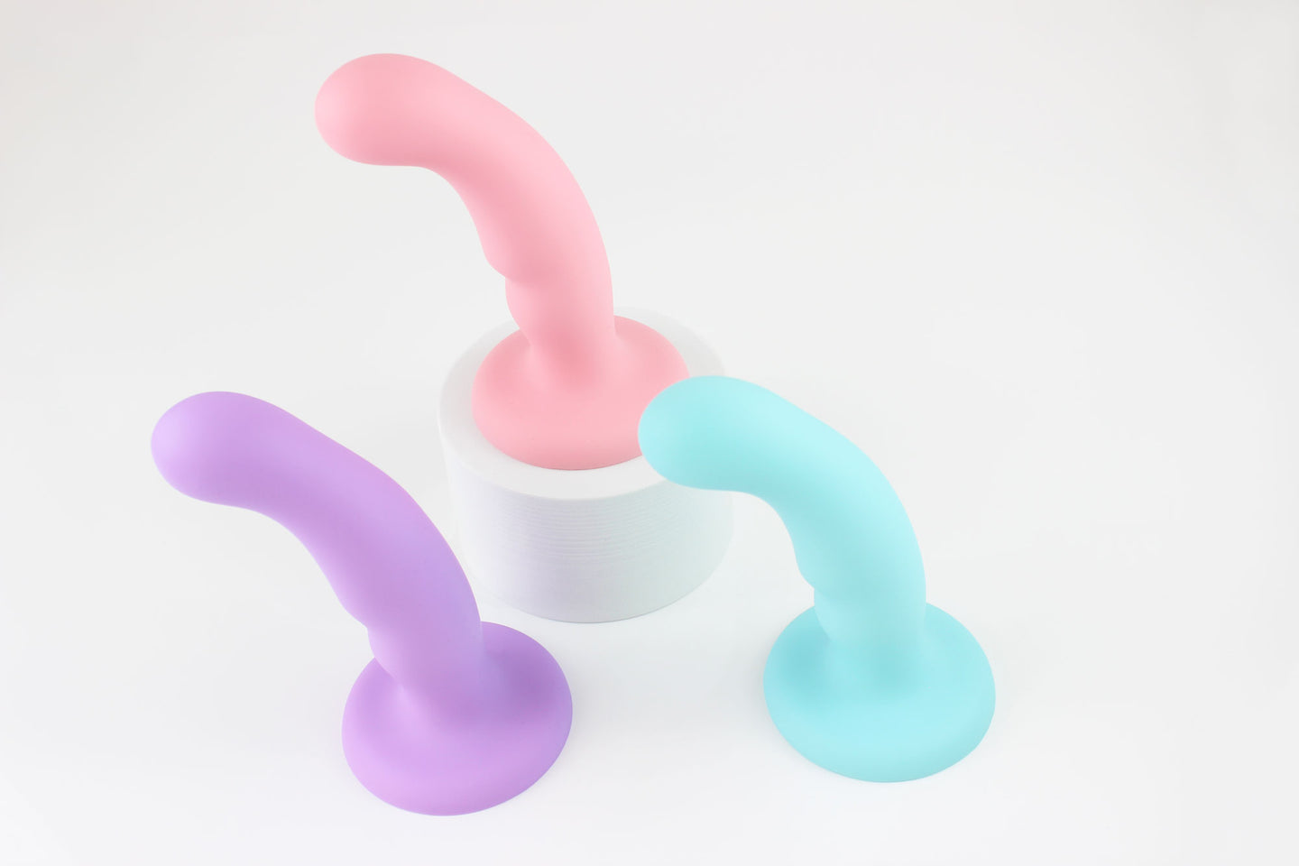 3 silicone dildos (light purple, light pink, and light blue) standing upright in front of white background