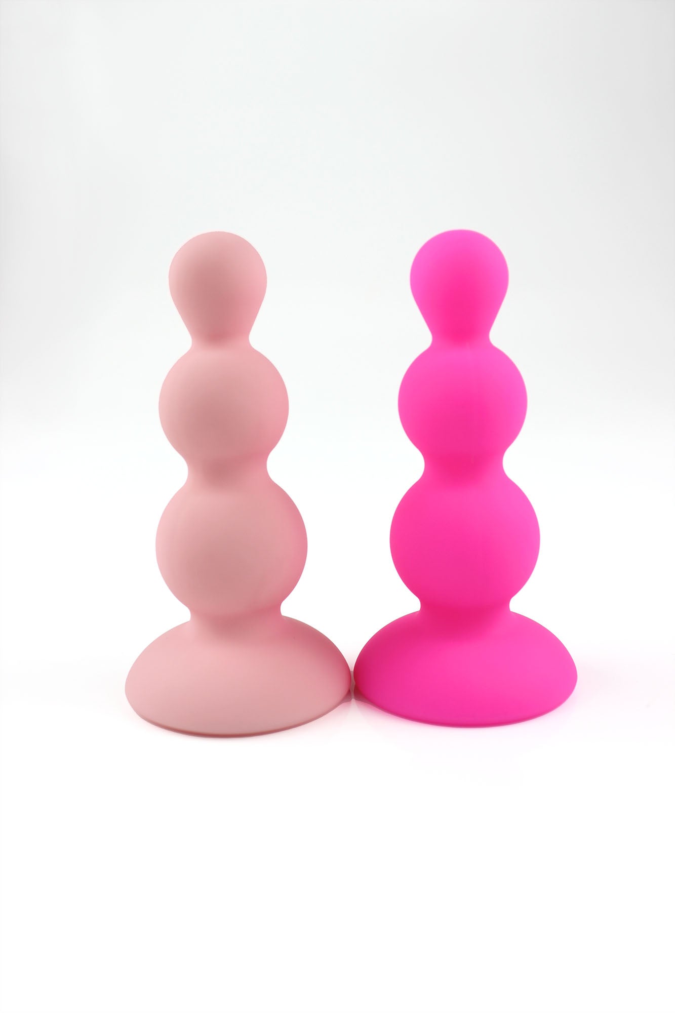 Hot pink beaded gem butt plug and peach pink beaded gem butt plug stood upright on white background