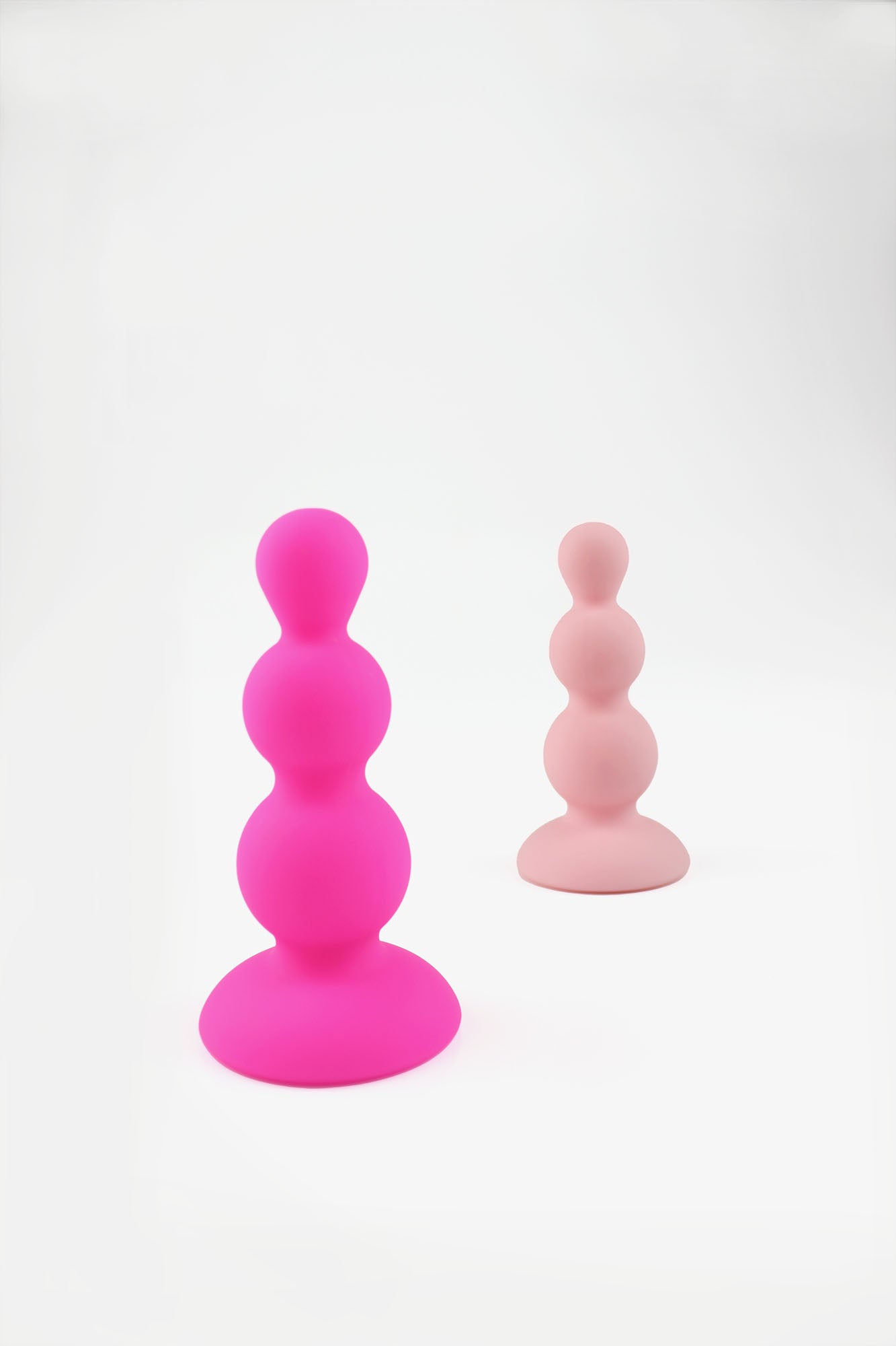 Hot pink beaded gem butt plug and peach pink beaded gem butt plug stood upright on white background