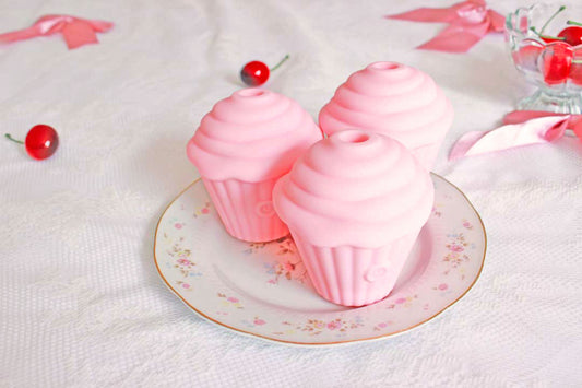 3 pink sucking cupcake vibrators on a plate surrounded by cherries and bows