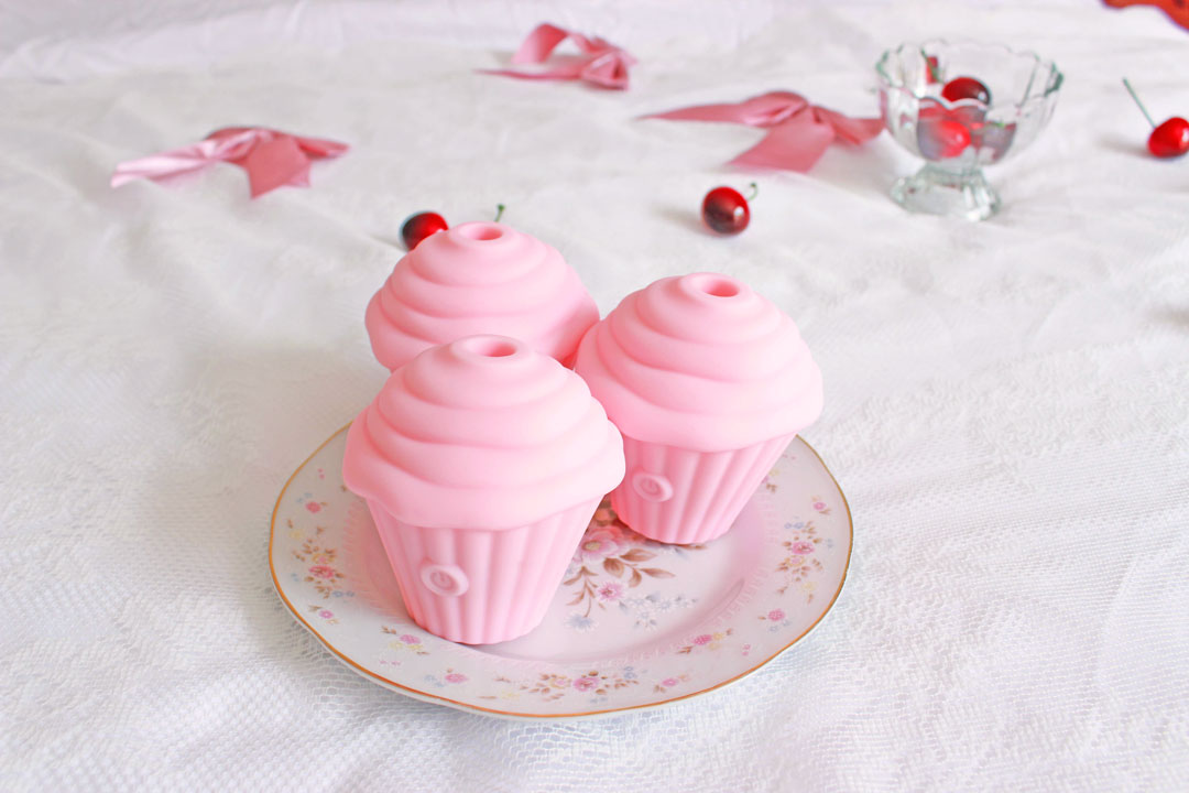 3 pink sucking cupcake vibrators on a plate surrounded by cherries and bows