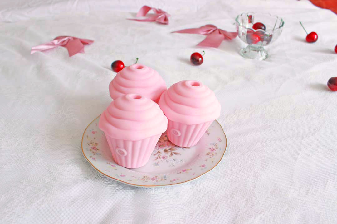 3 pink sucking cupcake vibrators on a plate surrounded by cherries and bows