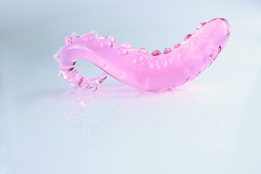 Side view of pink, bumpy Girthy Glass Tentacle Dildo in front of white background