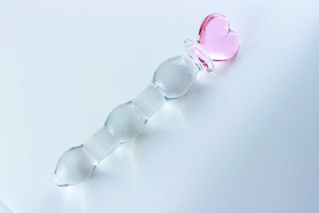 Knotted glass dildo with a pink heart base on a white background.