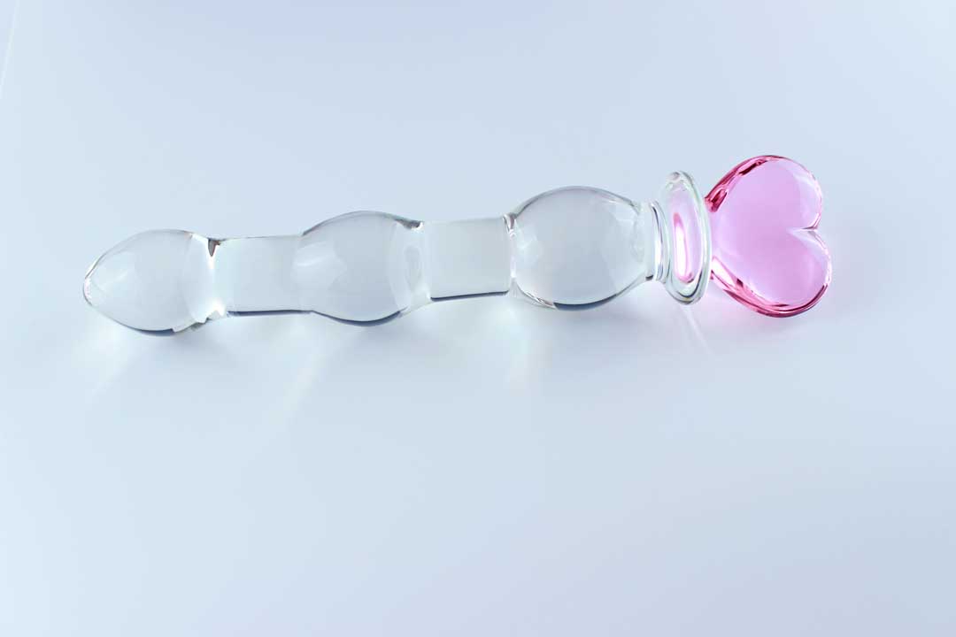 Knotted glass dildo with a pink heart base on a white background.