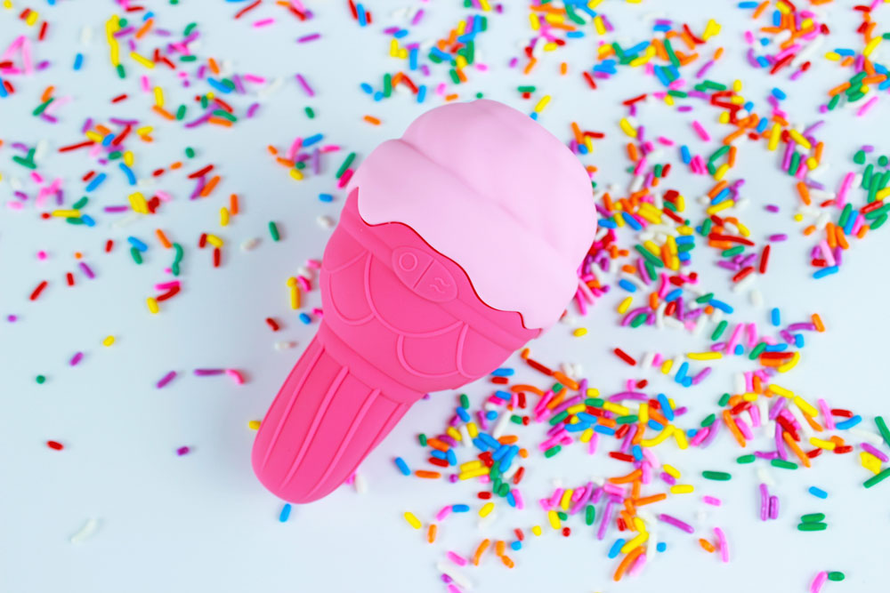 Pink silicone ice cream shaped vibrator on a white background with rainbow sprinkles