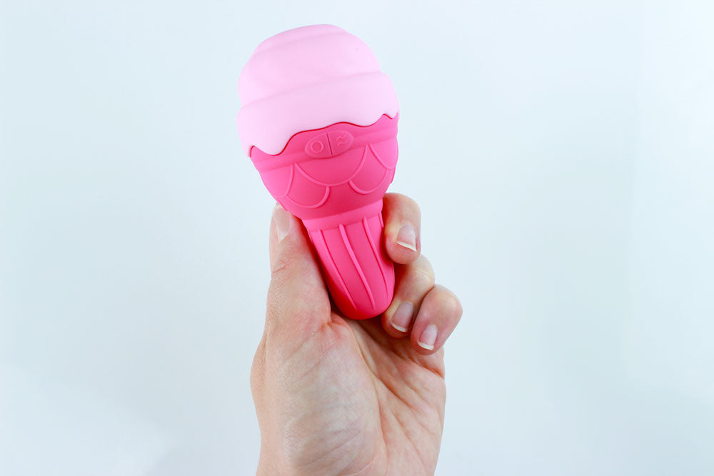 Hand holding pink silicone vibrator in front of a white background