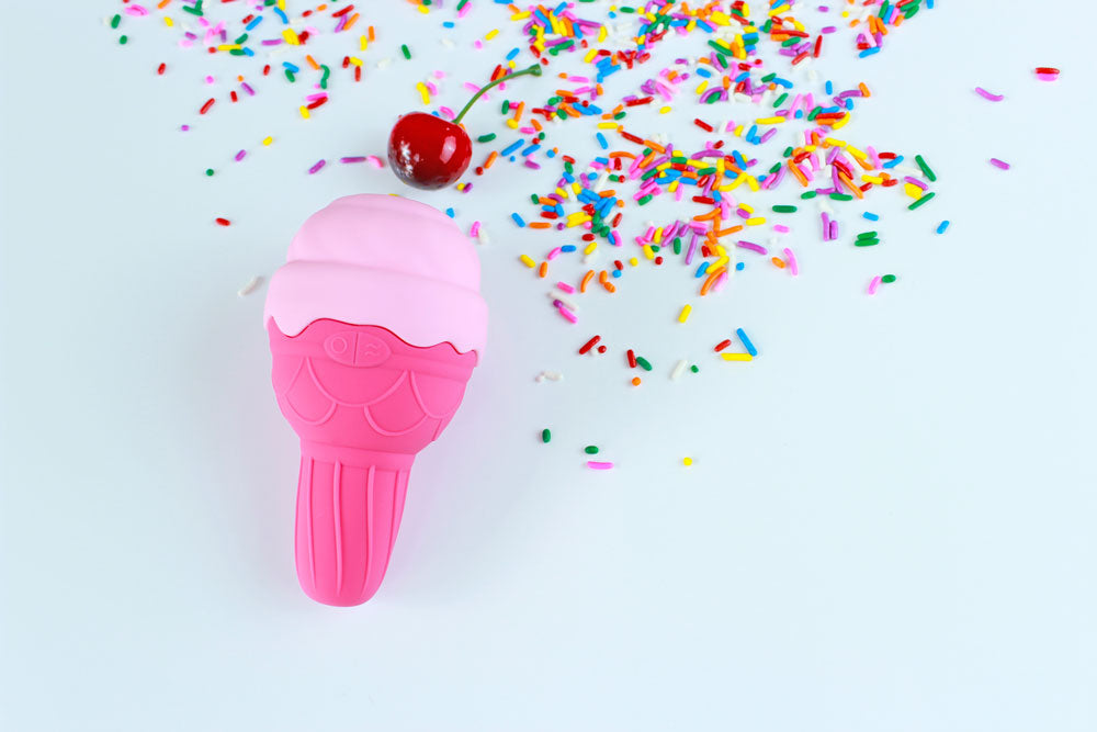 Pink silicone ice cream shaped vibrator on a white background with a cherry and rainbow sprinkles