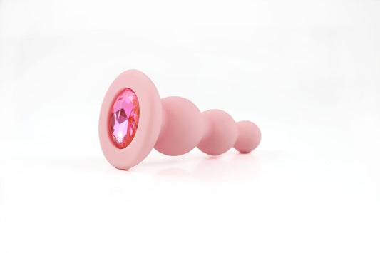 Peach pink beaded gem butt plug on a white background