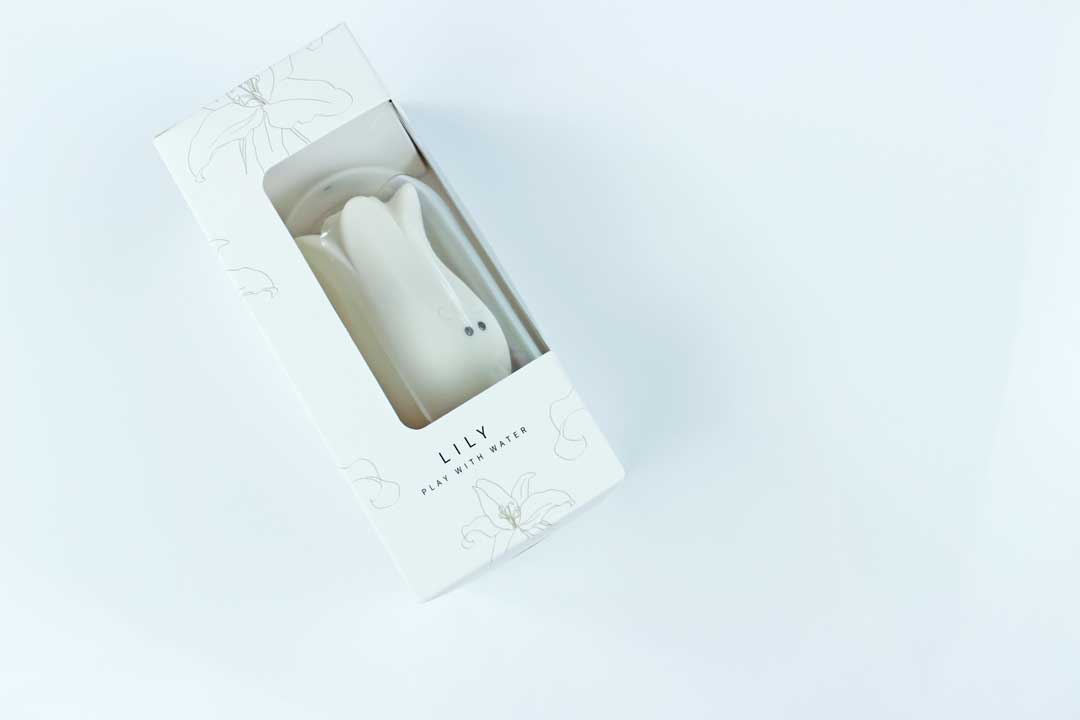 White lily suction vibrator in a white, floral print box with text reading "Lily - Play with Water"