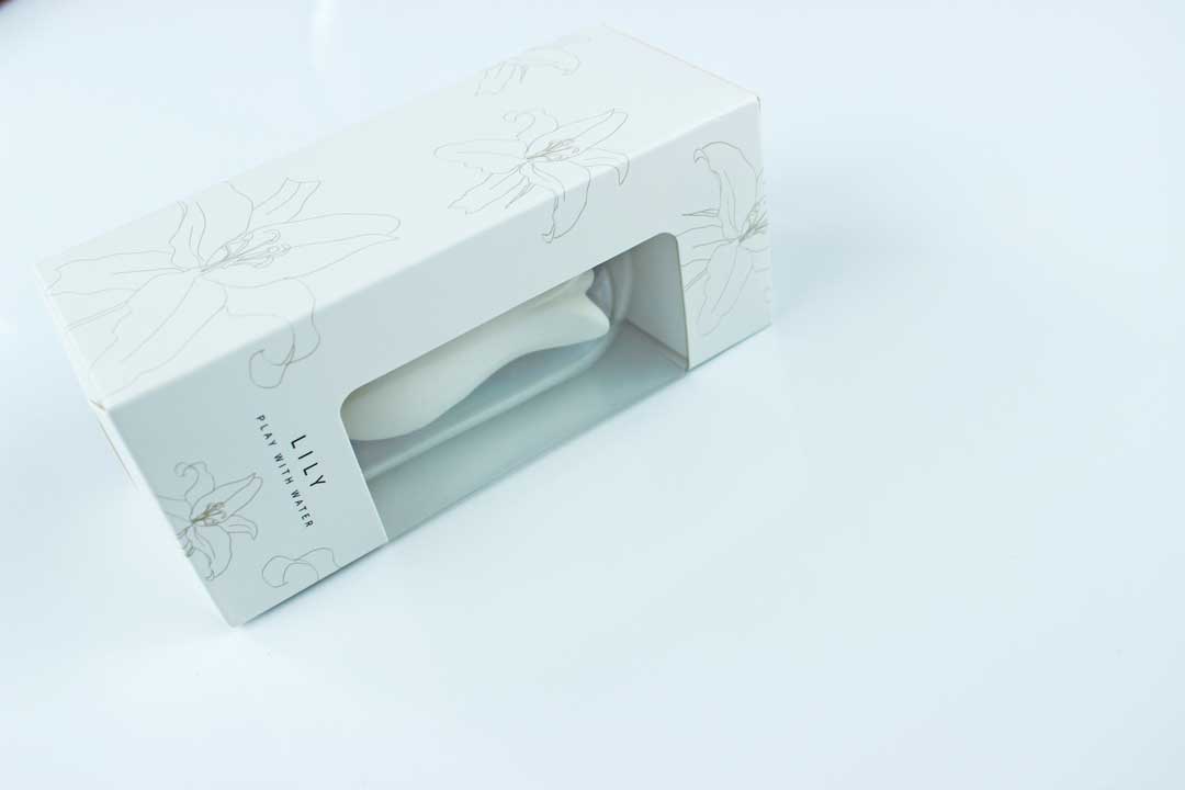 White lily suction vibrator in a white, floral print box with text reading "Lily - Play with Water"