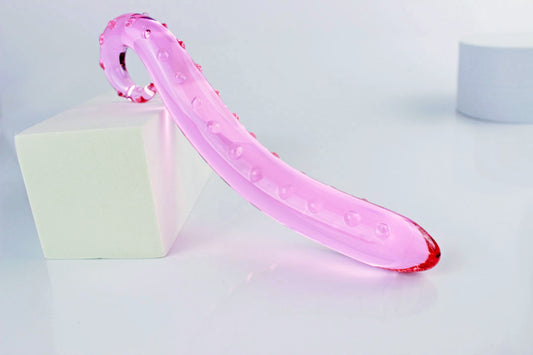 Side view of long pink glass tentacle propped against white rectangular shape on a white background