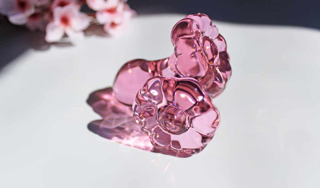 Two pink glass flower butt plugs stacked on a white background