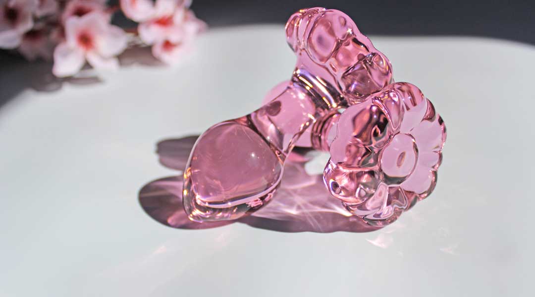 Two pink glass flower butt plugs stacked on a white background