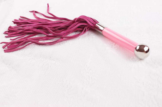 Flogger with pink suede falls and pink and silver handle on white lace background