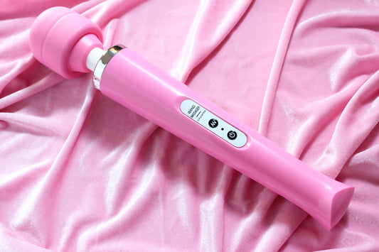 Pink massage wand vibrator laid on pink velvet fabric