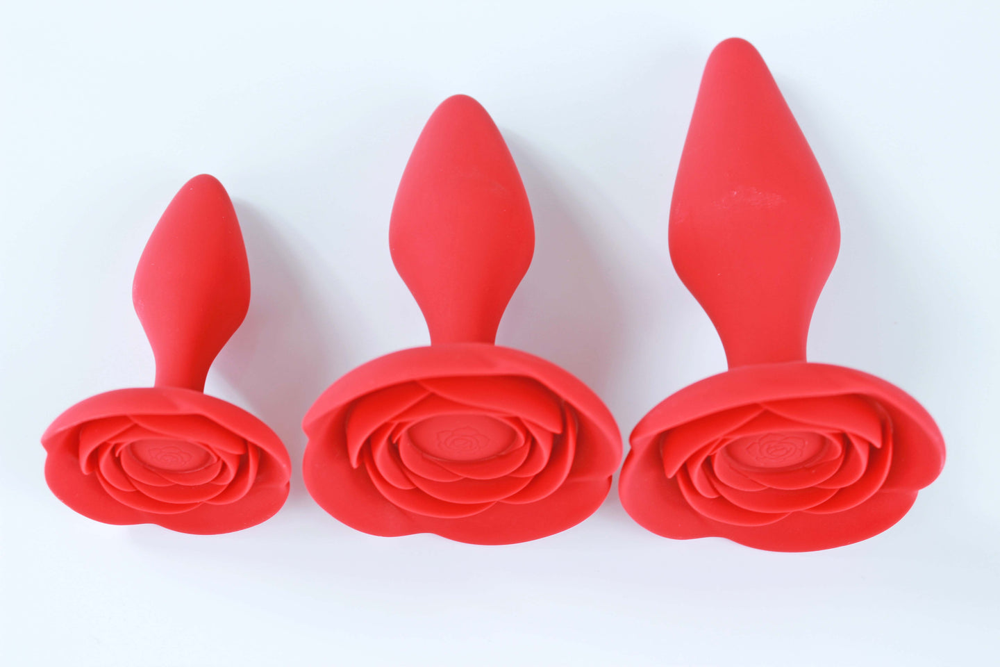 3  sizes of red rose anal training butt plugs on a white background