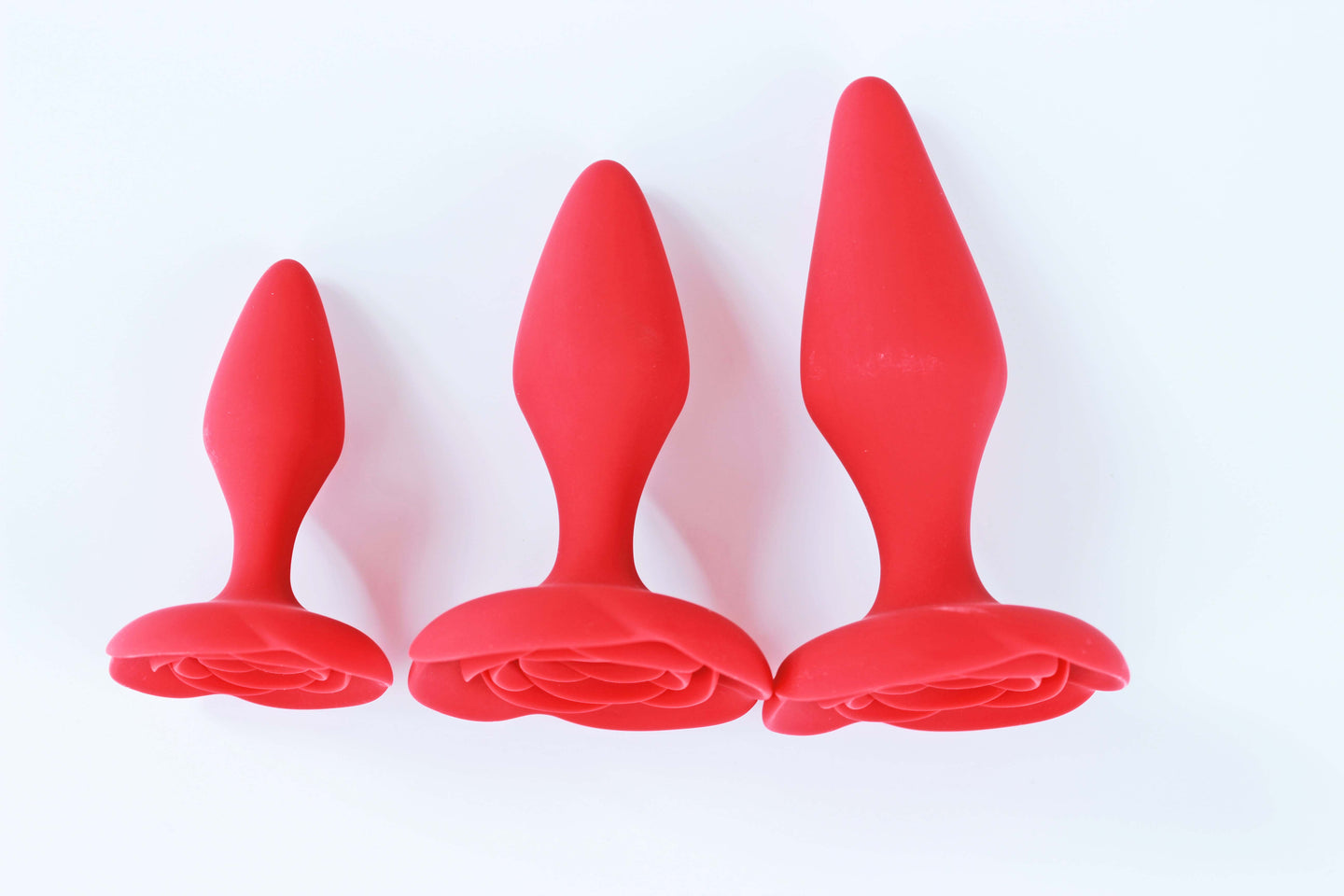 3 sizes of red rose anal training butt plugs on a white background