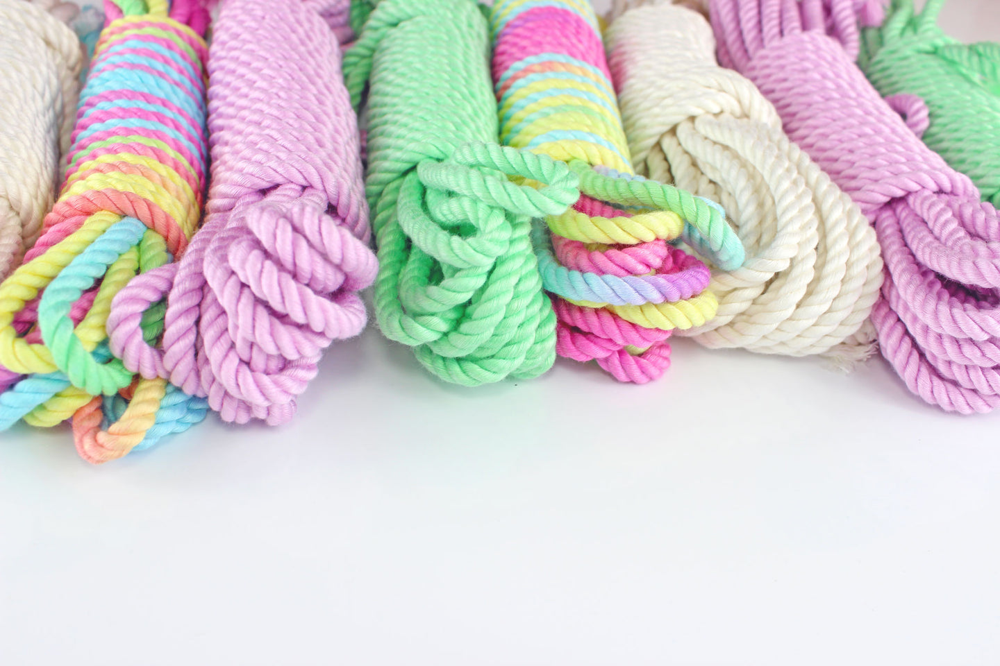 Bundles of bamboo silk rope in various colors (rainbow multicolor, lavender, mint, and white) on a white background
