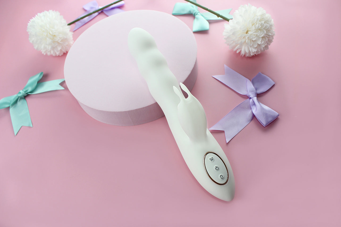 White bunny thruster dildo on pink background surrounded by purple and green bows and white flowers