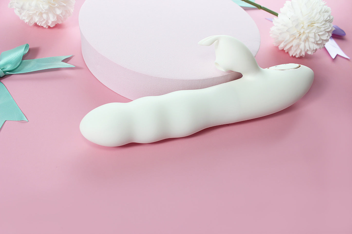 Side view of white bunny thruster dildo on pink background surrounded by purple and green bows and white flowers