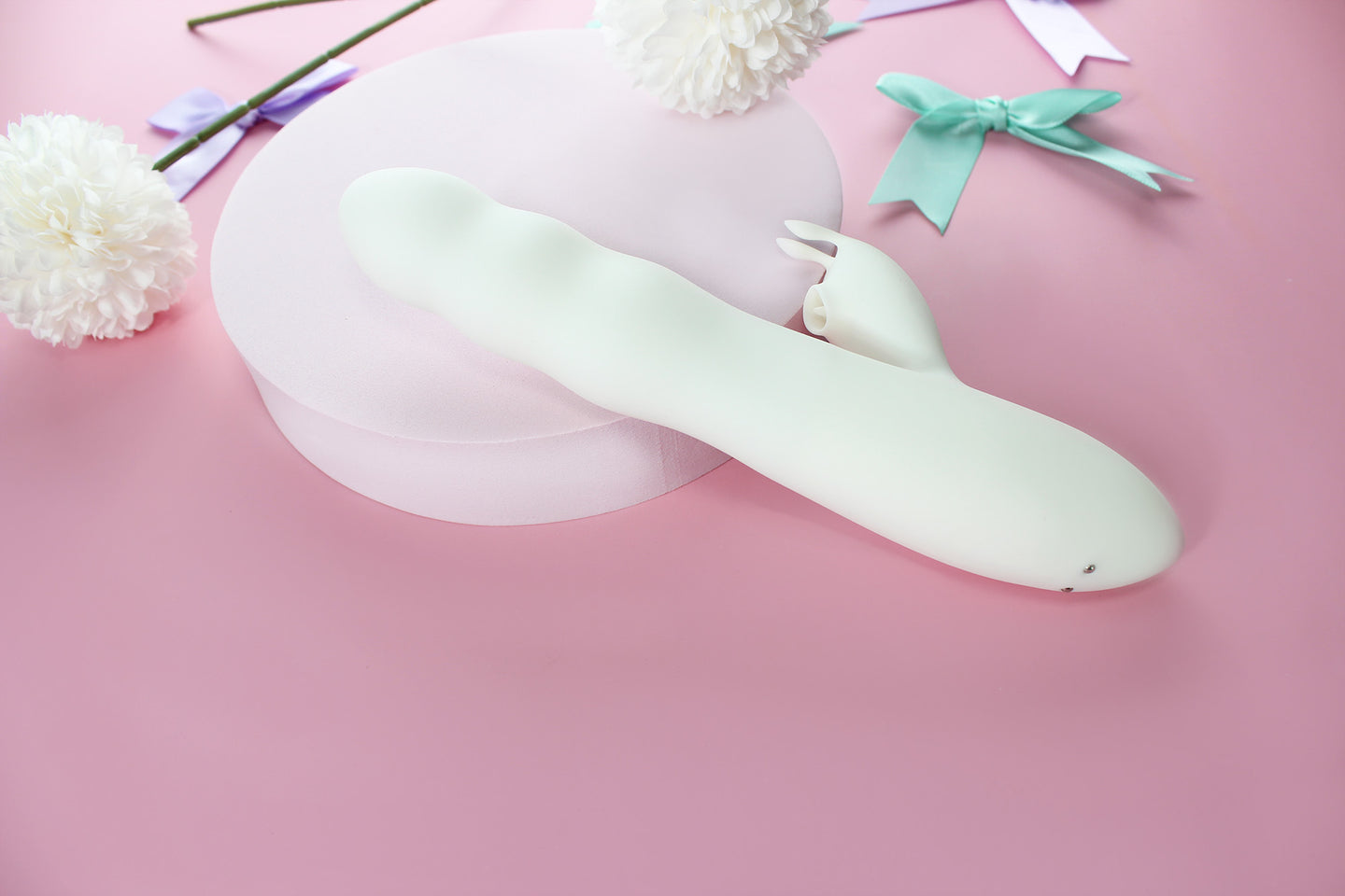 White bunny thruster dildo on pink background surrounded by purple and green bows and white flowers