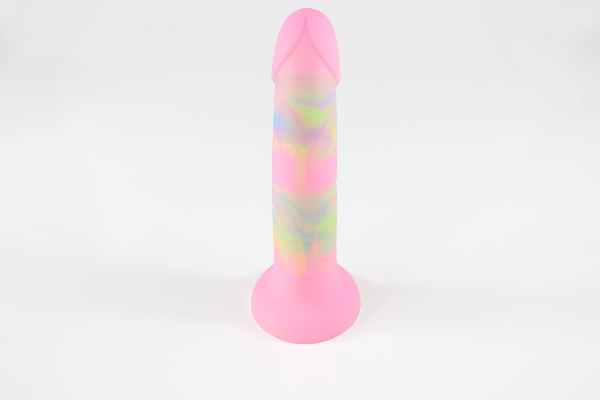 View of underside of pink, green, and blue marbled silicone dildo standing upright in front of white background