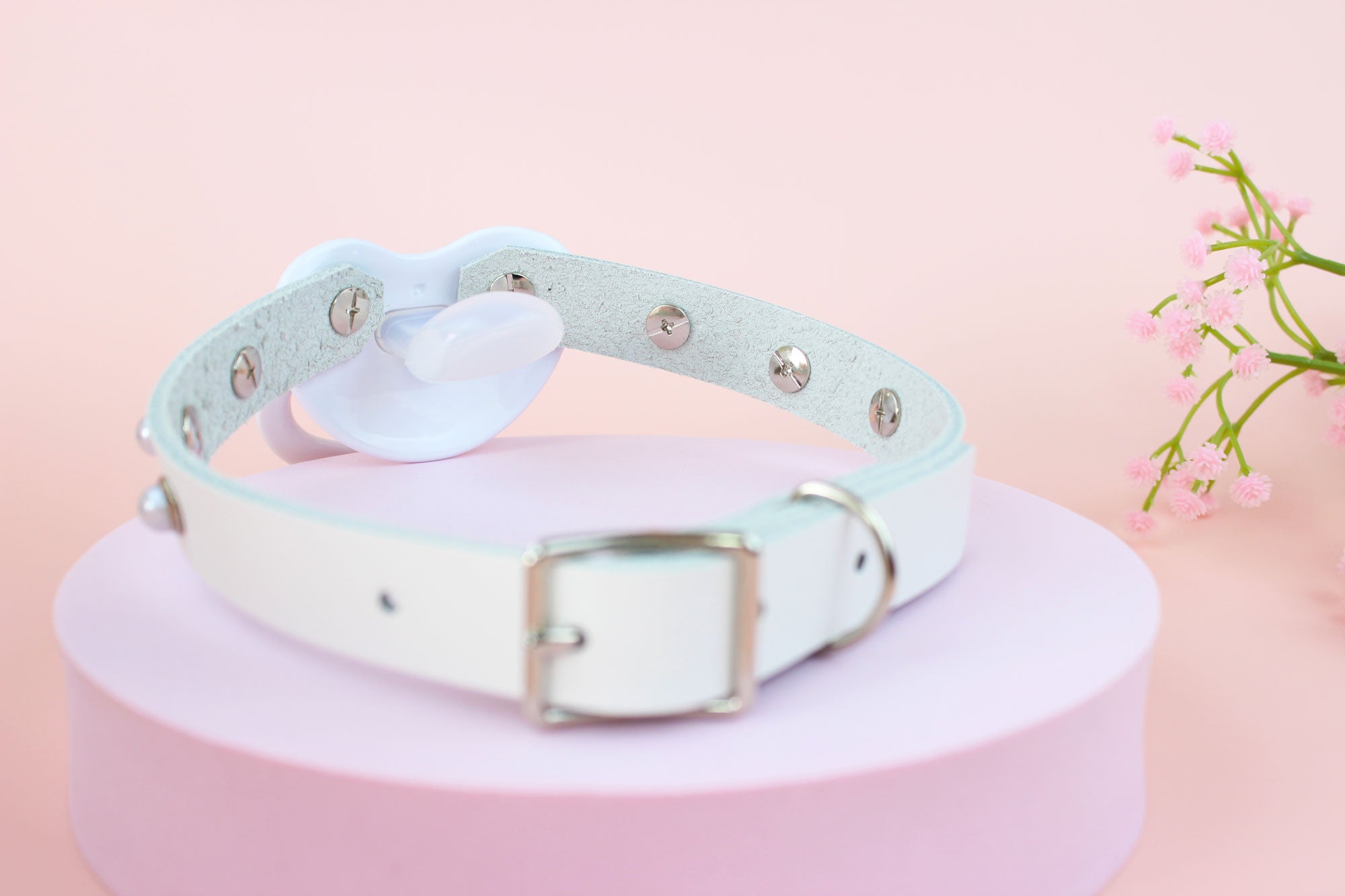 Back view of white bear pacifier gag in front of pink background