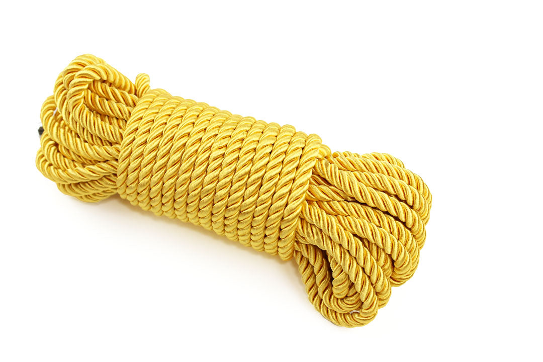 Bundle of gold satin shibari rope on a white background