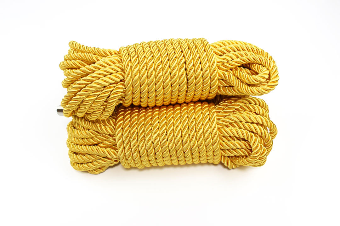 3 bundles of gold satin shibari rope on a white background