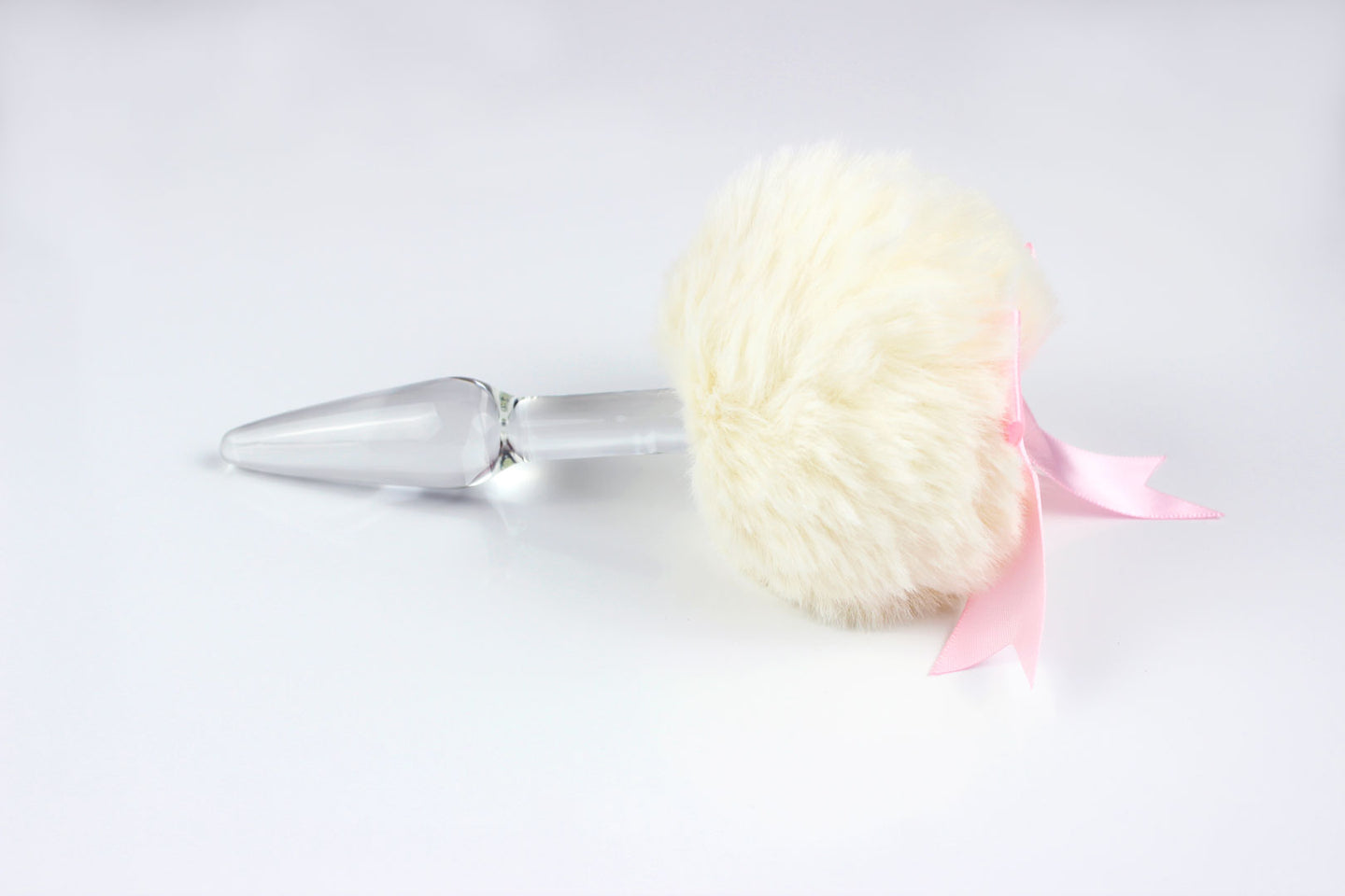 Side view of off-white bunny tail plug with pink bow on white background.