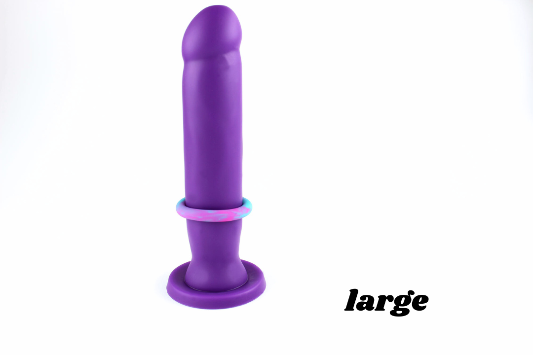 Large multicolored silicone cock ring on a purple dildo in front of a white background with corner text reading "large"