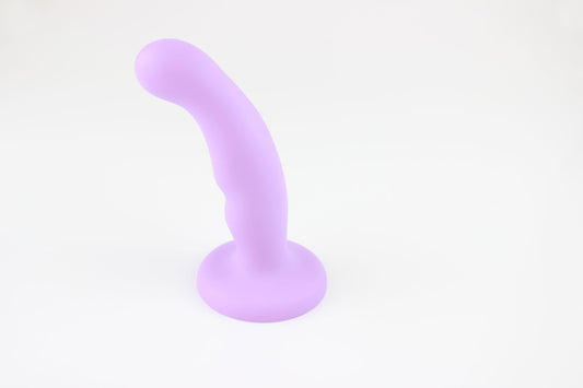Light purple silicone dildo standing upright on white background