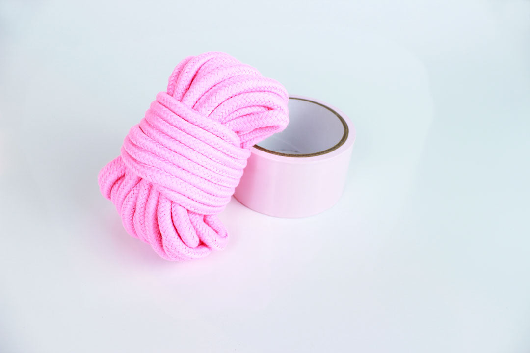 32 foot pink cotton shibari rope and roll of light pink bondage tape on white background