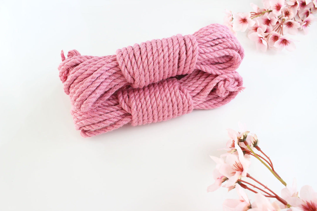 Two bundles of pink jute rope on a white background with pink flowers around the border.