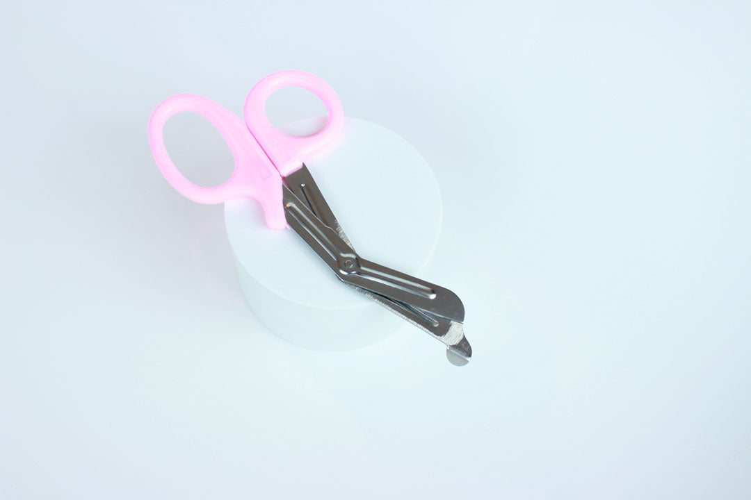 Bondage shears with light pink handles on white background