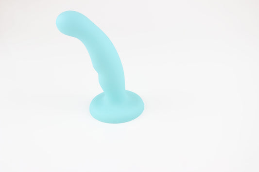 Light blue silicone dildo standing upright on white background