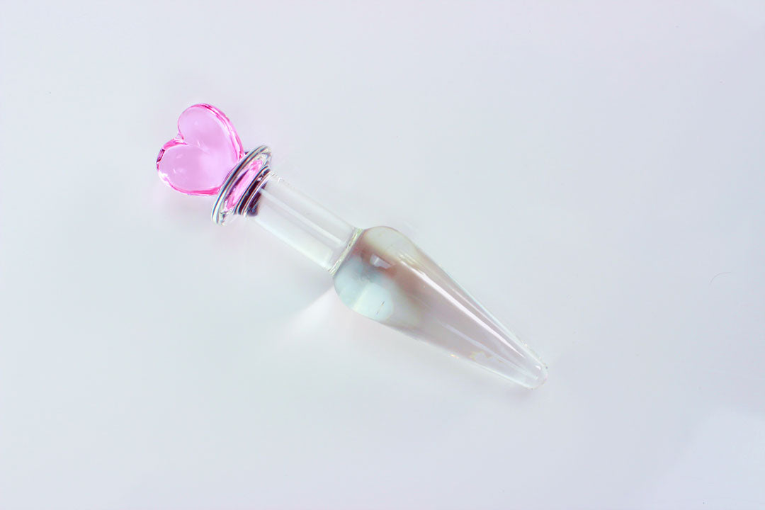 Tapered glass butt plug with pink heart base on a white background.