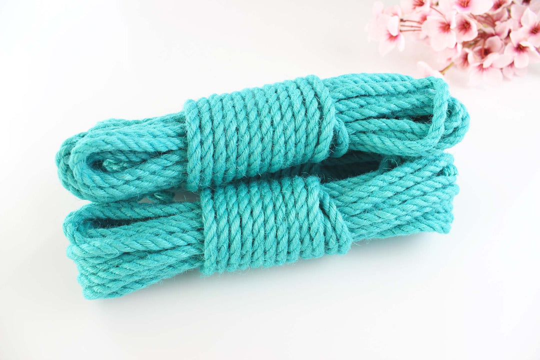 Multiple bundles of turquoise jute rope stacked on top of each other against a white background with pink flowers.