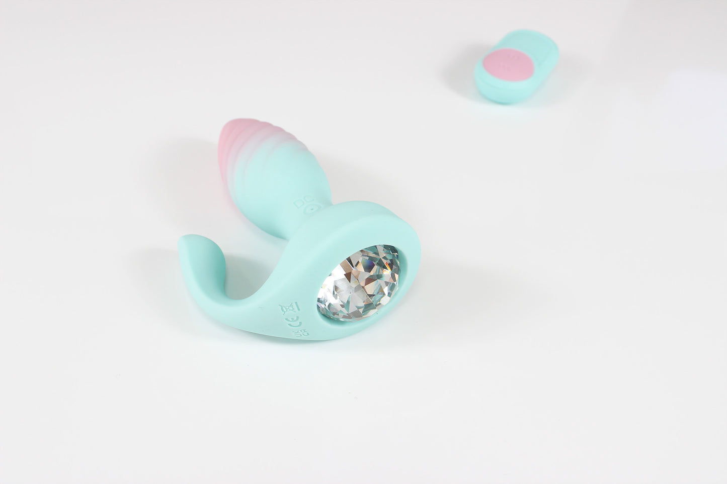Pastel blue and pink vibrating gem butt plug with remote on white background