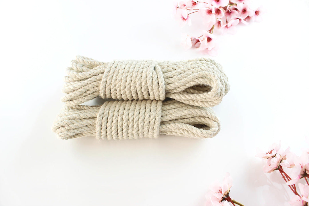  Multiple bundles of white jute rope stacked on top of each other against a white background with pink flowers.