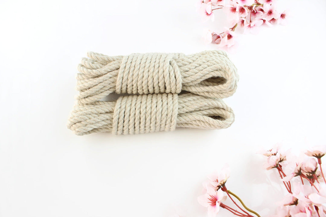 Multiple bundles of white jute rope stacked on top of each other against a white background with pink flowers.