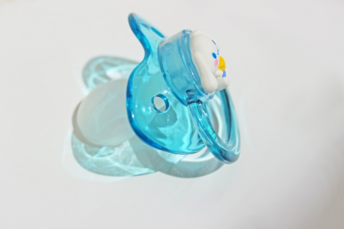 Pup charm clear blue adult pacifier on a white background.