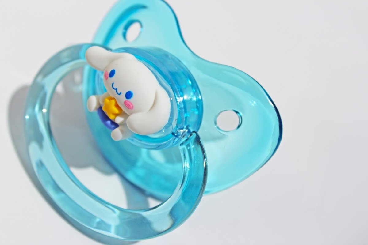 Pup charm clear blue adult pacifier on a white background.