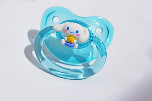 Pup charm clear blue adult pacifier on a white background.