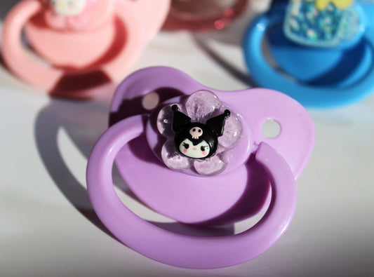 Purple adult pacifier with cute charm.