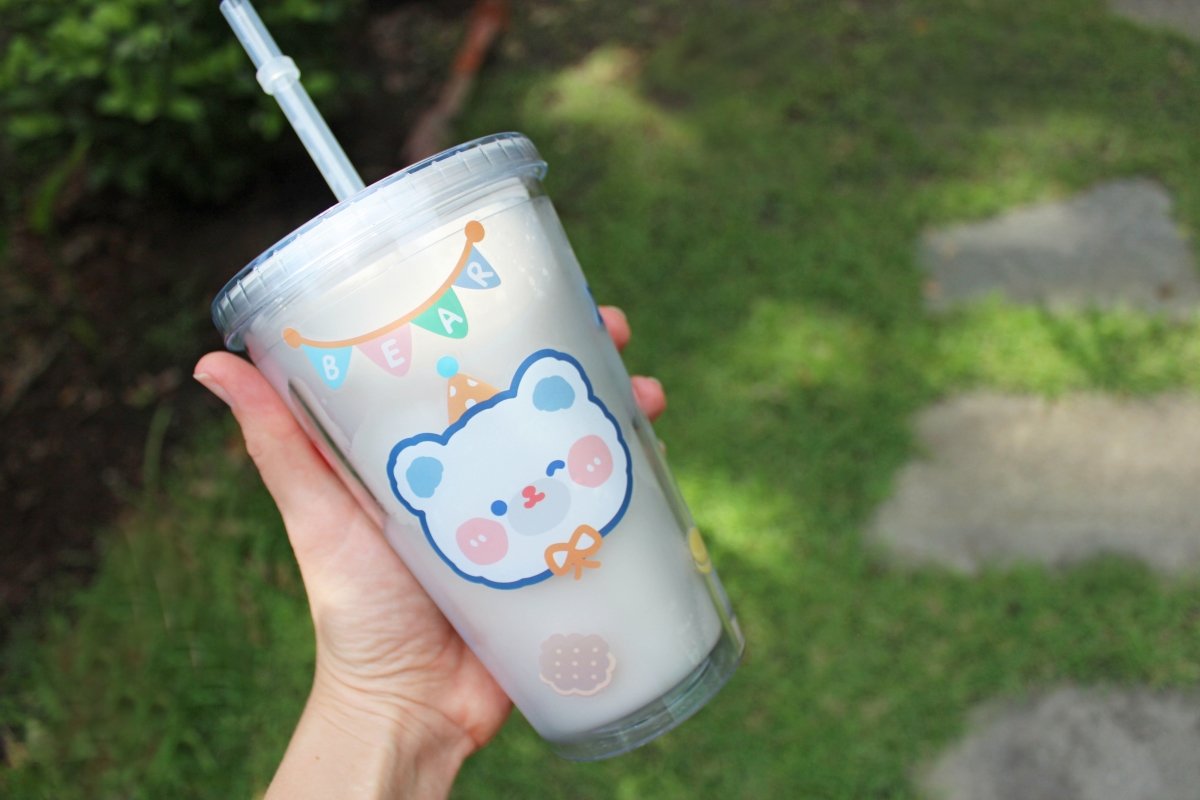 Someone holding up a kawaii 16oz tumbler cup to show off the pattern outdoors.