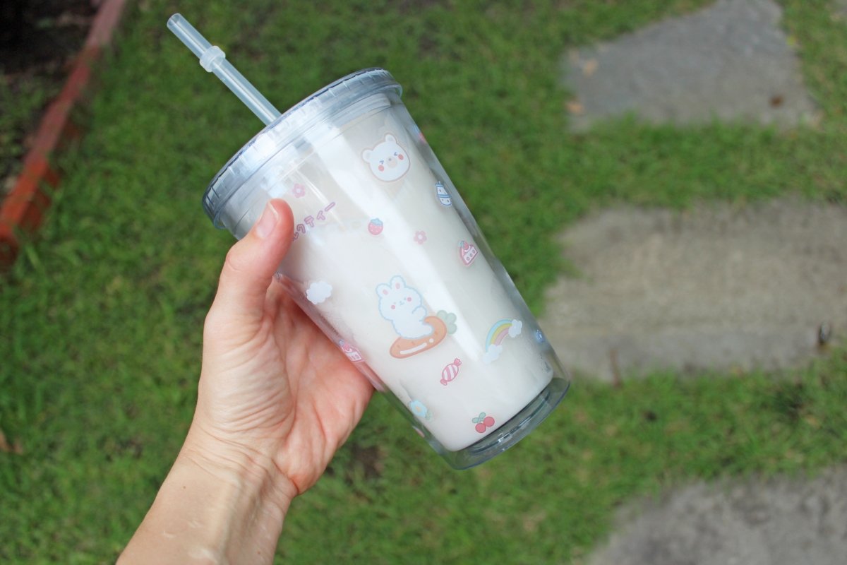 Someone holding up a kawaii 16oz tumbler cup to show off the pattern outdoors.